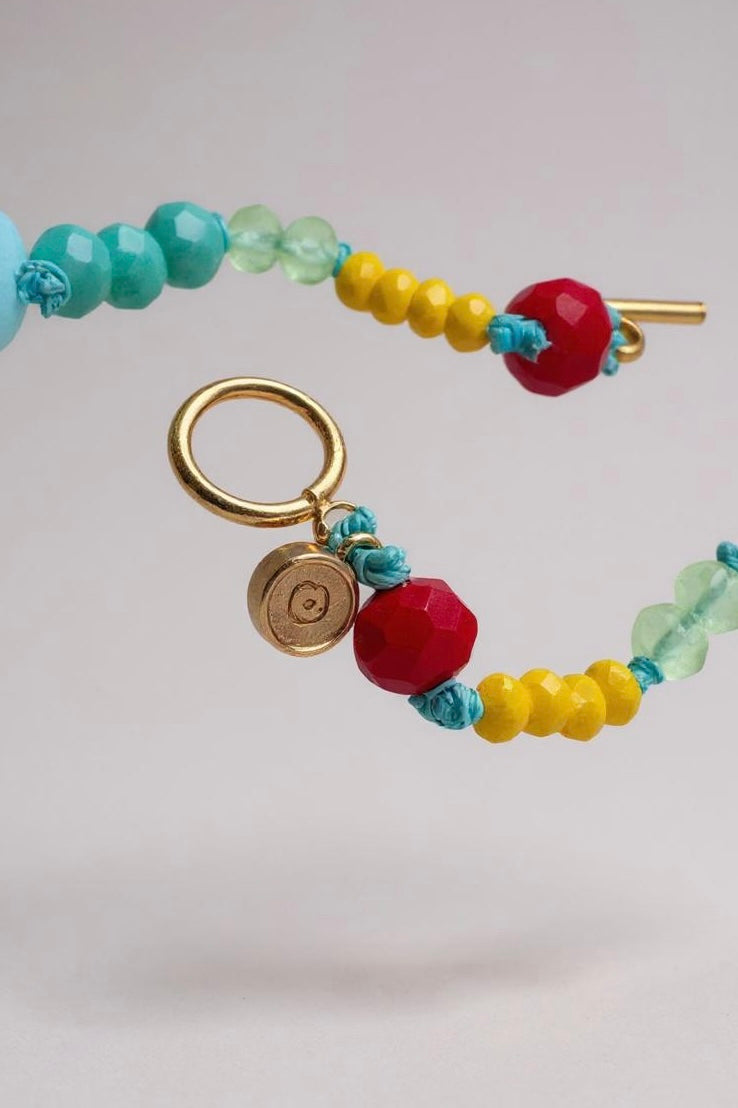 collar de cuentas de colores con cierre dorado sobre fondo claro.