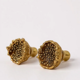 Primer plano de dos aretes Topos Coca M en bronce bañado en oro con textura de granulación en vidrio detallada, sobre un fondo neutro claro.