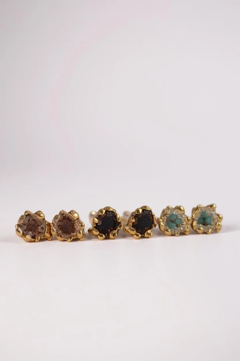 Seis aretes Topos Coca S dispuestos en línea horizontal sobre fondo claro, cada uno con engaste dorado de volantes relleno de granulación de vidrio y pintura en tonos marrón, negro, verde, turquesa y más.