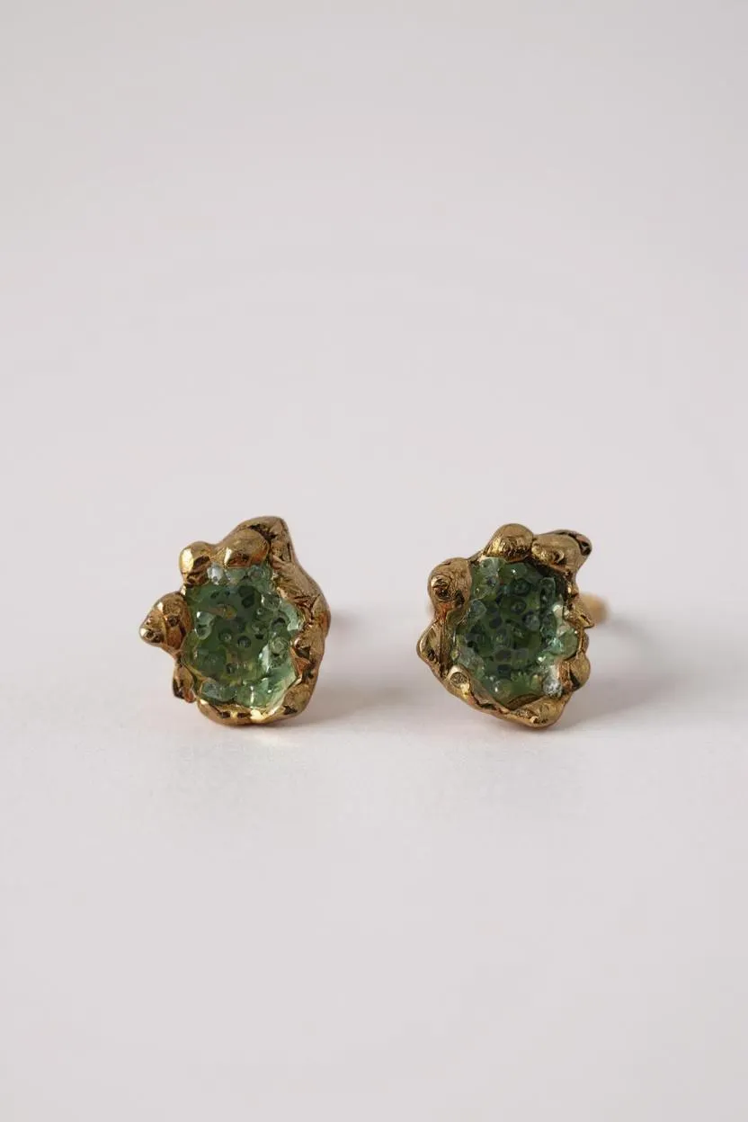 Par de aretes Topos Coca S con granulación de vidrio y pintura verde en engastes dorados, sobre fondo blanco.