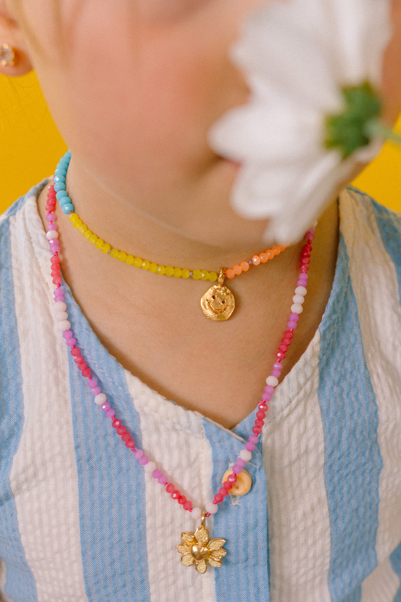 Primer plano de niña usando el Collar Margarita con dije dorado pintado a mano y cadena de hilo con cristales.