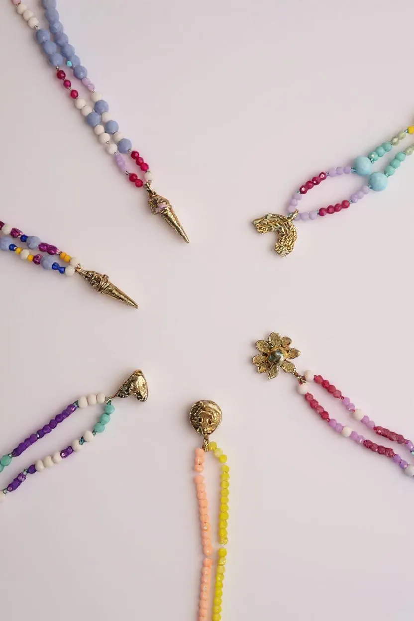 Conjunto de collares artesanales con dijes dorados pintados a mano y cadenas de colores vibrantes.