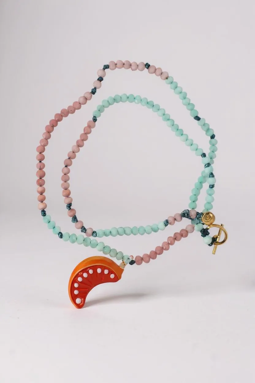 Disposición plana del Collar Naranja sobre fondo blanco, con cuentas alternadas en verde menta y rosa y un colgante de media luna naranja brillante.