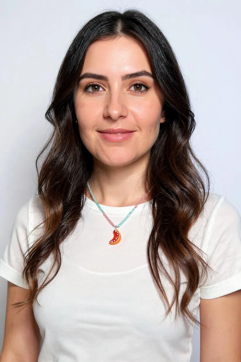 Retrato de una mujer de cabello oscuro con blusa blanca y el Collar Naranja, centrado en su cuello sobre fondo blanco.