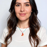Retrato de una mujer de cabello oscuro con blusa blanca y el Collar Naranja, centrado en su cuello sobre fondo blanco.