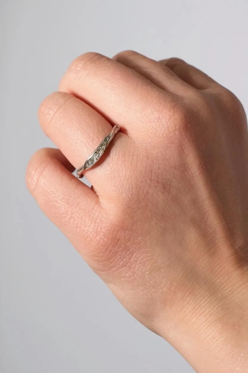 Anillo de plata con diamantes de laboratorio en un dedo, mostrando cómo luce puesto en la mano.