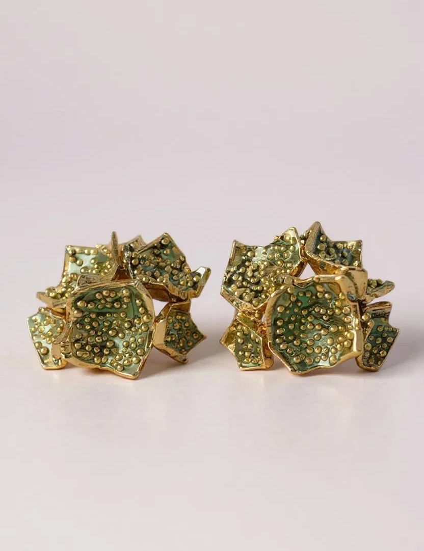 Par de aretes Galaxea en color sage: bañados en oro, con forma de galaxia y cúmulos de gránulos de vidrio verde salvia, sobre un fondo claro.