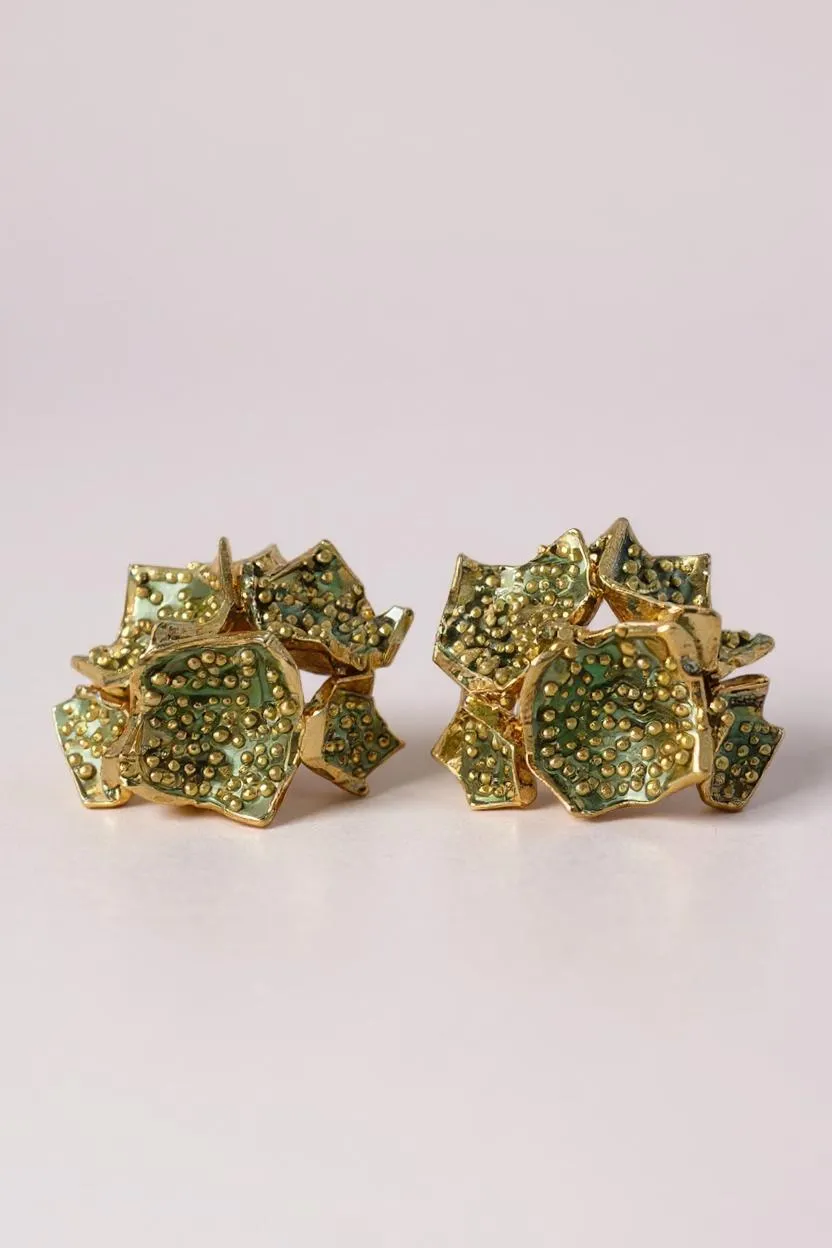 Par de aretes Galaxea en color sage: bañados en oro, con forma de galaxia y cúmulos de gránulos de vidrio verde salvia, sobre un fondo claro.
