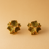 Dos aretes Galaxea en color sage: bañados en oro, con forma floral y gránulos de vidrio verde salvia, colocados lado a lado sobre un fondo beige cálido.