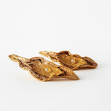 Disposición plana de dos Aretes Lechuga variante Mustard en bronce bañado en oro, pintados a mano en rust con granulación de vidrio, sobre fondo blanco.