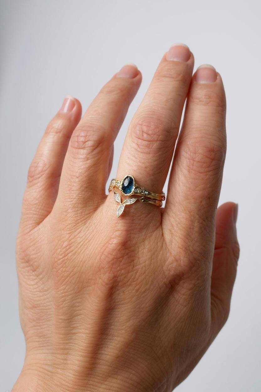 Anillo con zafiro de Montana y diamantes de laboratorio en oro amarillo 10k puesto en una mano, fotografiado sobre fondo neutro claro.