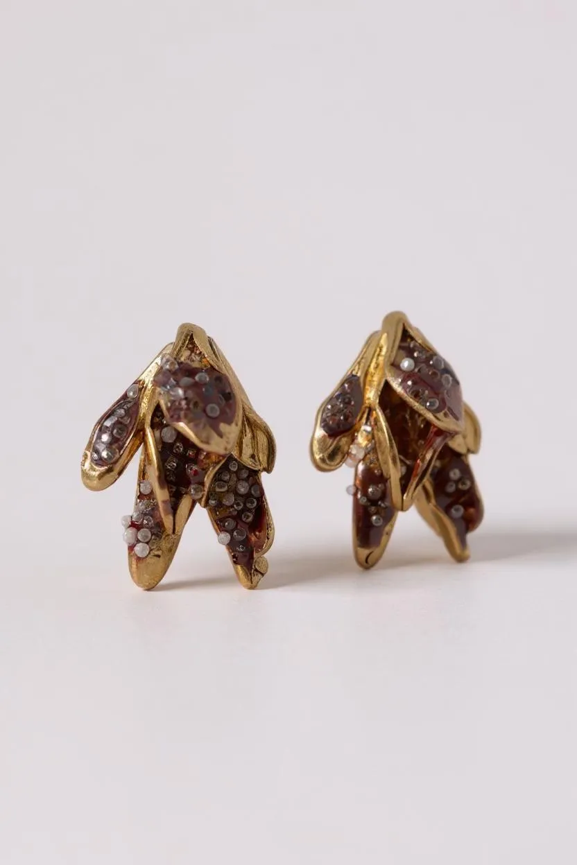 Par de aretes topos Nebula Mini en bronce bañado en oro, pintados a mano en rust y con granulación de vidrio, sobre fondo blanco.