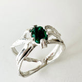 Anillo de plata esterlina con esmeralda de laboratorio engastada en banda orgánica esculpida, visto de frente sobre fondo neutro.