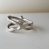 ista lateral del anillo con esmeralda de laboratorio mostrando el diseño orgánico de banda dividida en plata esterlina pulida.