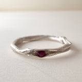 vista frontal de anillo nido, fabricado en plata con un rubí en el centro, sobre fondo claro