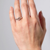 Anillo de plata esterlina con piedra del sol puesto en una mano, fotografiado sobre fondo gris claro.