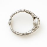 Anillo de plata esterlina con piedra del sol puesto en una mano, fotografiado sobre fondo gris claro