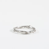 Anillo Nido Incrustado en plata esterlina con pequeño diamante de laboratorio incrustado en una banda orgánica retorcida, sobre fondo blanco.