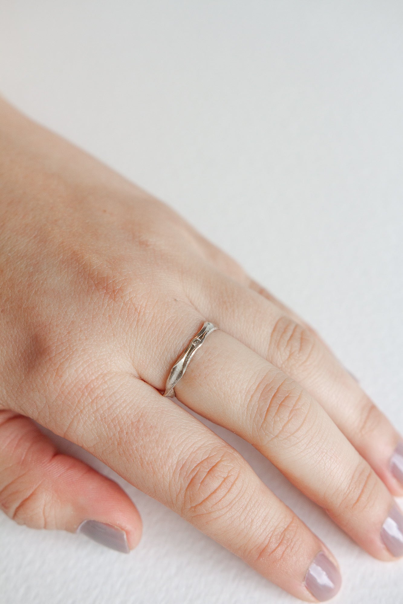 Anillo Nido en plata esterlina con diamante de laboratorio puesto en una mano, fotografiado sobre superficie neutra.