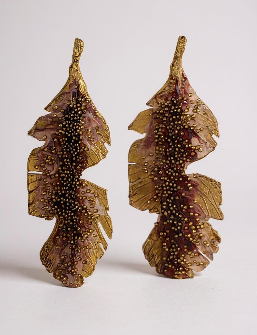 Par de aretes Hojas de Plátano en bronce bañado en oro pintado a mano en rust detalle de granulación de vidrio, sobre fondo blanco.