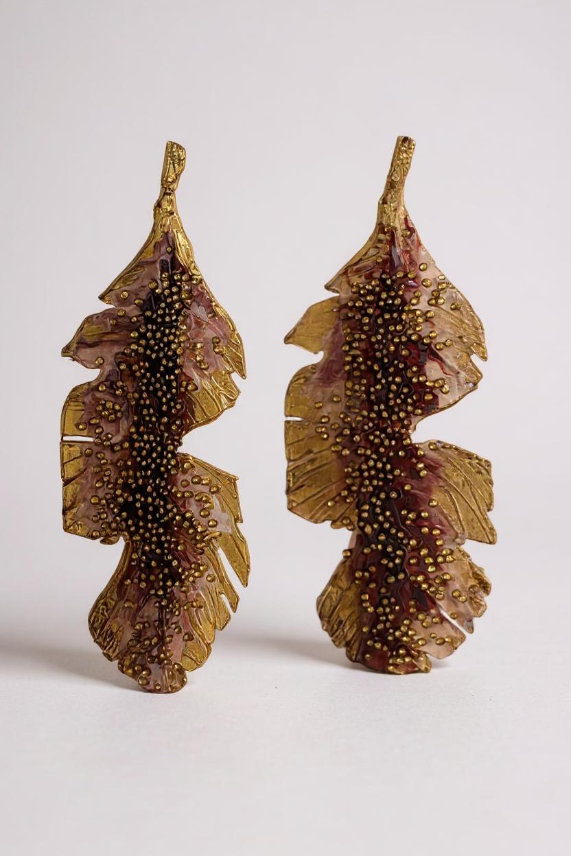 Par de aretes Hojas de Plátano en bronce bañado en oro pintado a mano en rust detalle de granulación de vidrio, sobre fondo blanco.