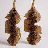 Par de aretes Hojas de Plátano en bronce bañado en oro pintado a mano en rust detalle de granulación de vidrio, sobre fondo blanco.