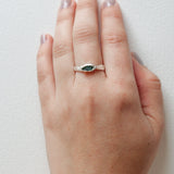 Anillo Refugio con esmeralda en bruto en plata esterlina puesto en una mano, visto desde otro ángulo contra fondo blanco.