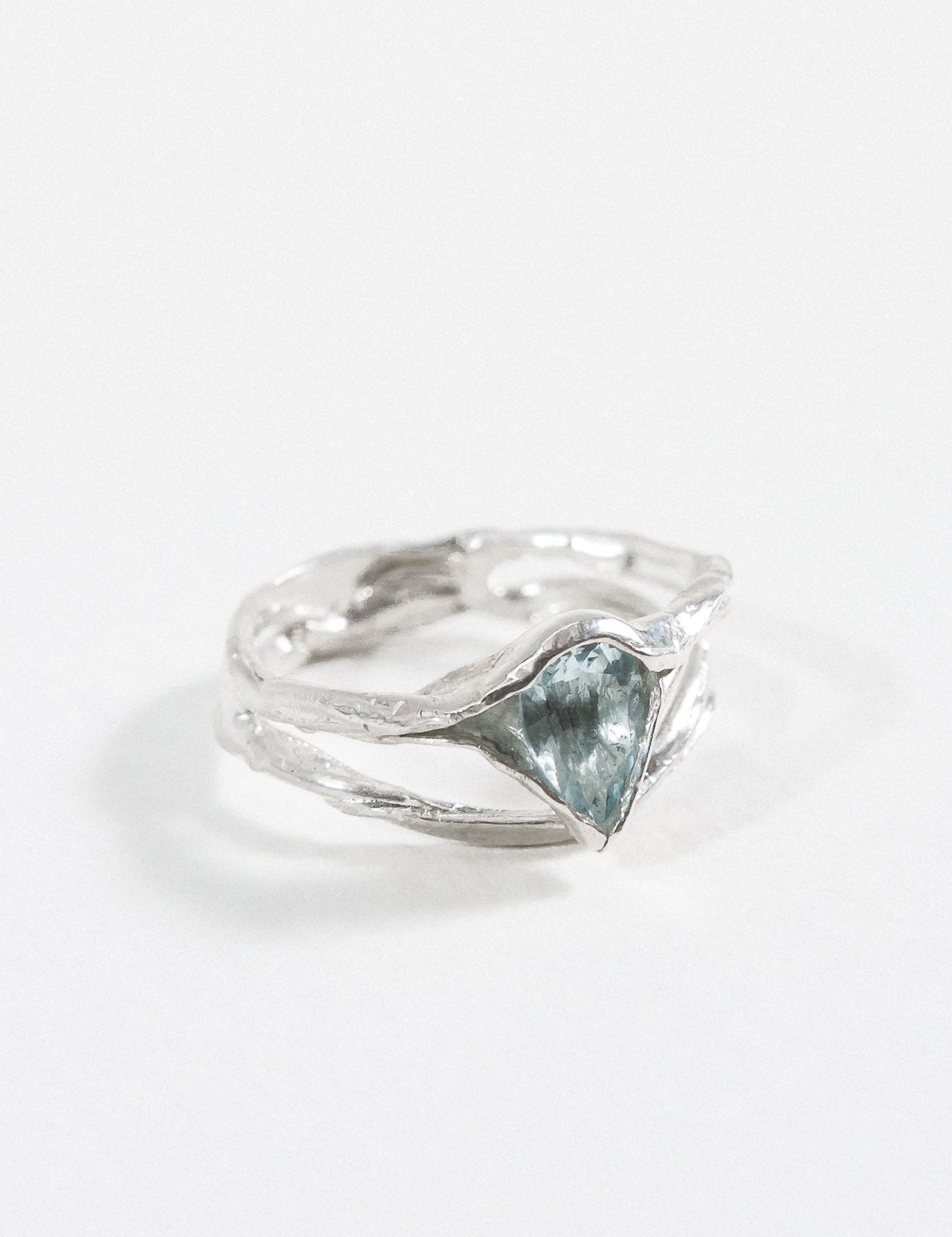 “Vista diagonal del anillo de plata esterlina con una piedra facetada de aguamarina.