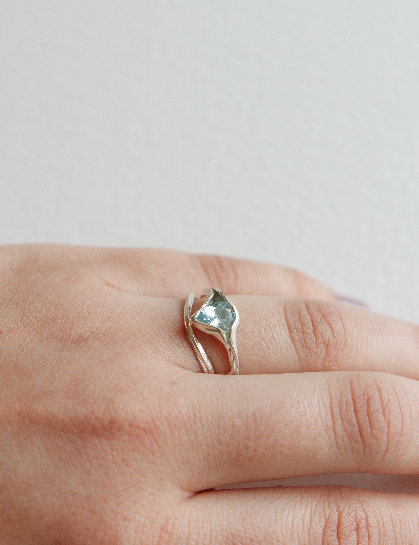 Anillo de plata con aguamarina puesto en la mano, mostrando su brillo natural y engaste orgánico.