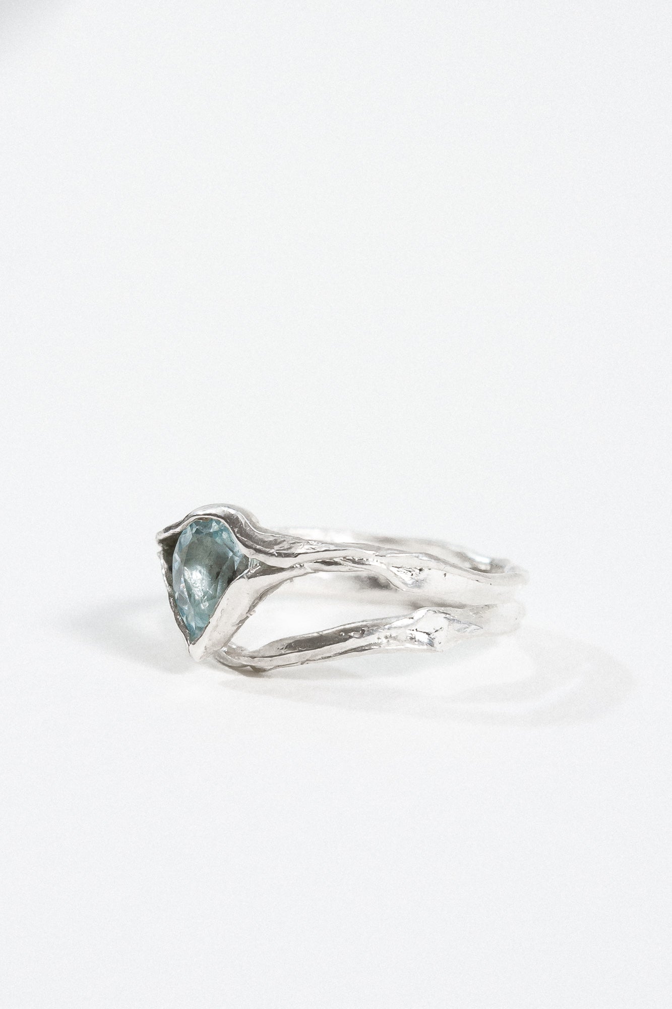 Vista lateral del anillo con aguamarina que resalta la banda de plata texturizada.