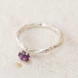 Vista superior del anillo de plata esterlina con una amatista de 4 mm, sobre tela neutra, destacando su textura orgánica y artesanal.