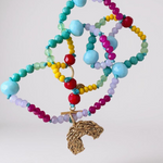 collar  de cuentas de cristales multicolor con un dije dorado en forma de arcoíris sobre fondo blanco.