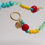 collar de cuentas de colores con cierre dorado sobre fondo claro.