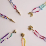Collares de cuentas de colores con varios colgantes sobre un fondo claro.