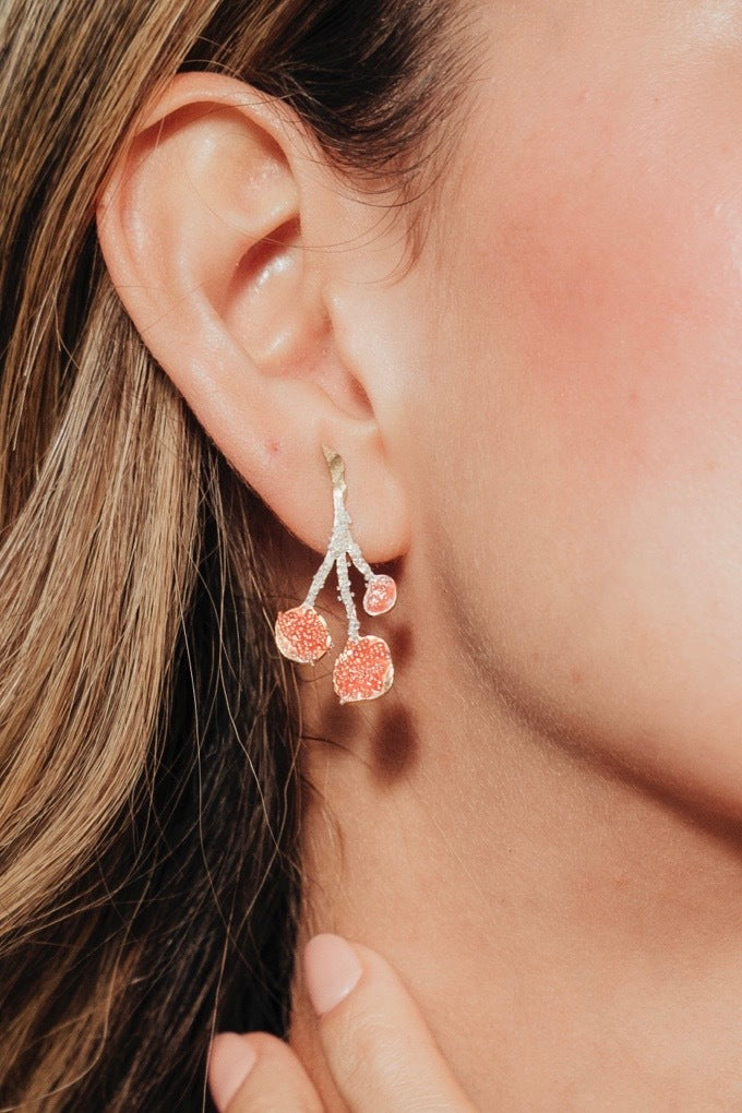 Primer plano de la modelo luciendo un Arete Agraz, mostrando su diseño botánico y acabado artesanal.