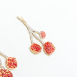 Detalle macro del diseño texturizado y pintado a mano de los Aretes Agraz en tonos rojos.