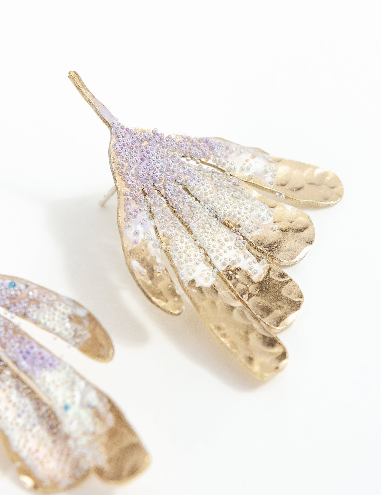 Aretes Ala de Flor  fotografiados de cerca, mostrando perlas de vidrio y acabado artesanal