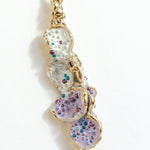 Detalle cercano del diseño texturizado y pintado a mano de los Aretes Azahar en tonos lavanda.