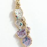 Detalle cercano del diseño texturizado y pintado a mano de los Aretes Azahar en tonos lavanda.