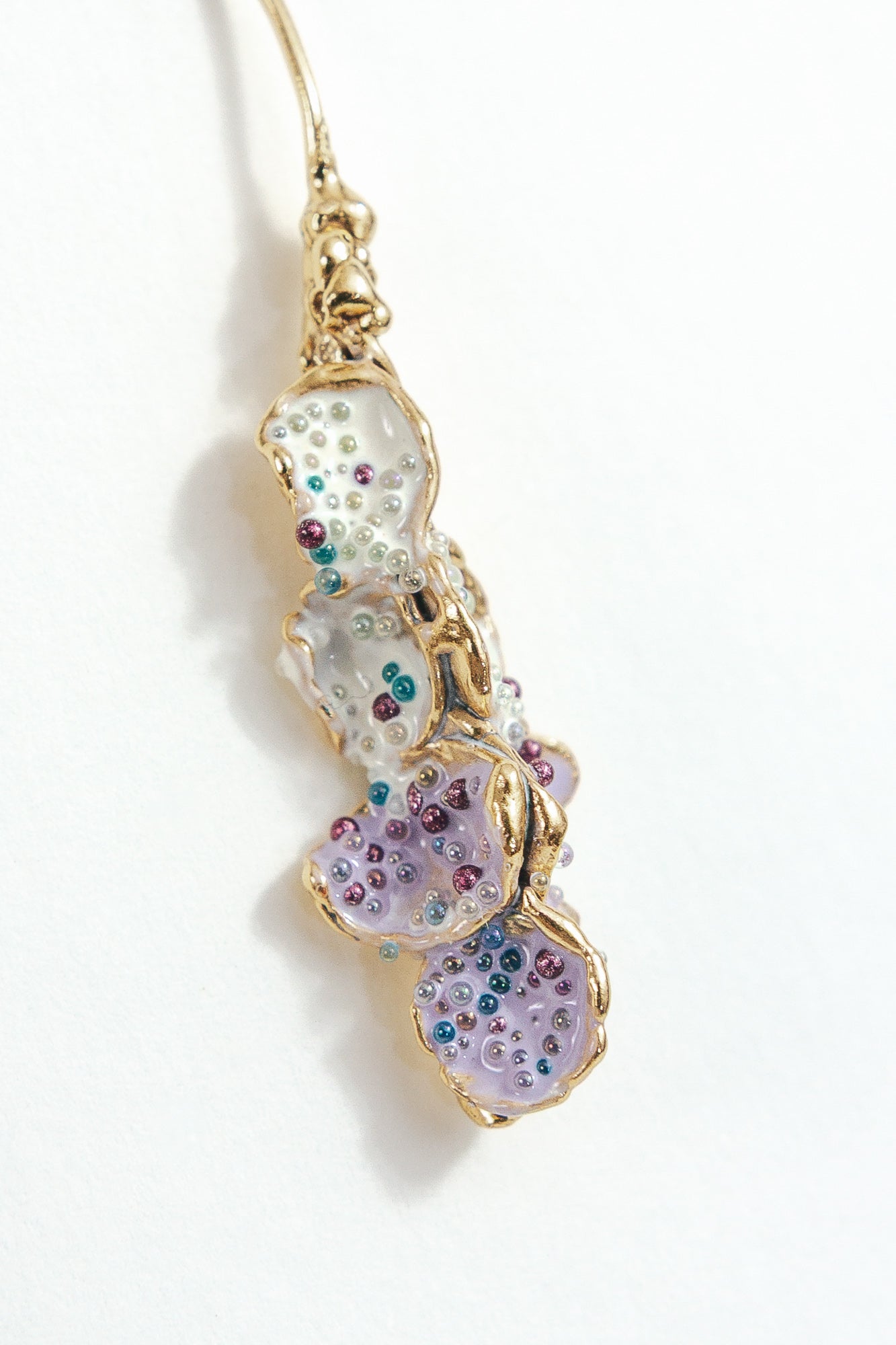 Detalle cercano del diseño texturizado y pintado a mano de los Aretes Azahar en tonos lavanda.