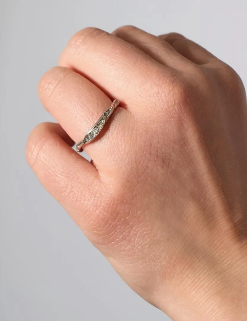 Anillo de plata con diamantes de laboratorio en un dedo, mostrando cómo luce puesto en la mano.