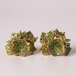 Par de aretes Galaxea en color sage: bañados en oro, con forma de galaxia y cúmulos de gránulos de vidrio verde salvia, sobre un fondo claro.