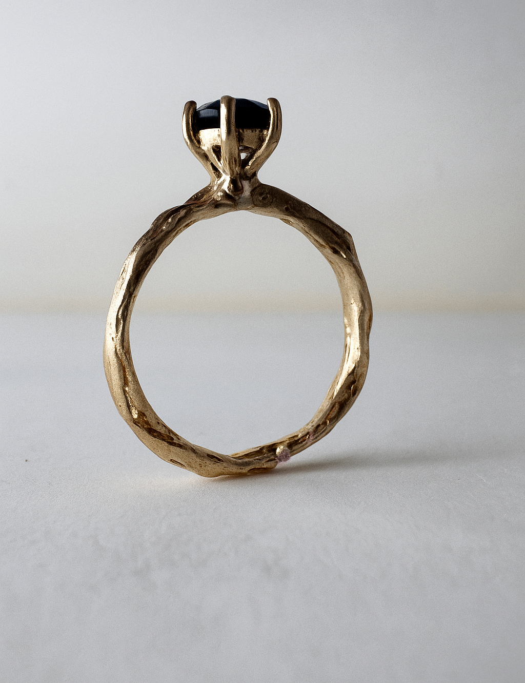 Anillo de oro amarillo 10k con topacio Londres engastado en una banda orgánica esculpida, visto de frente sobre fondo claro.