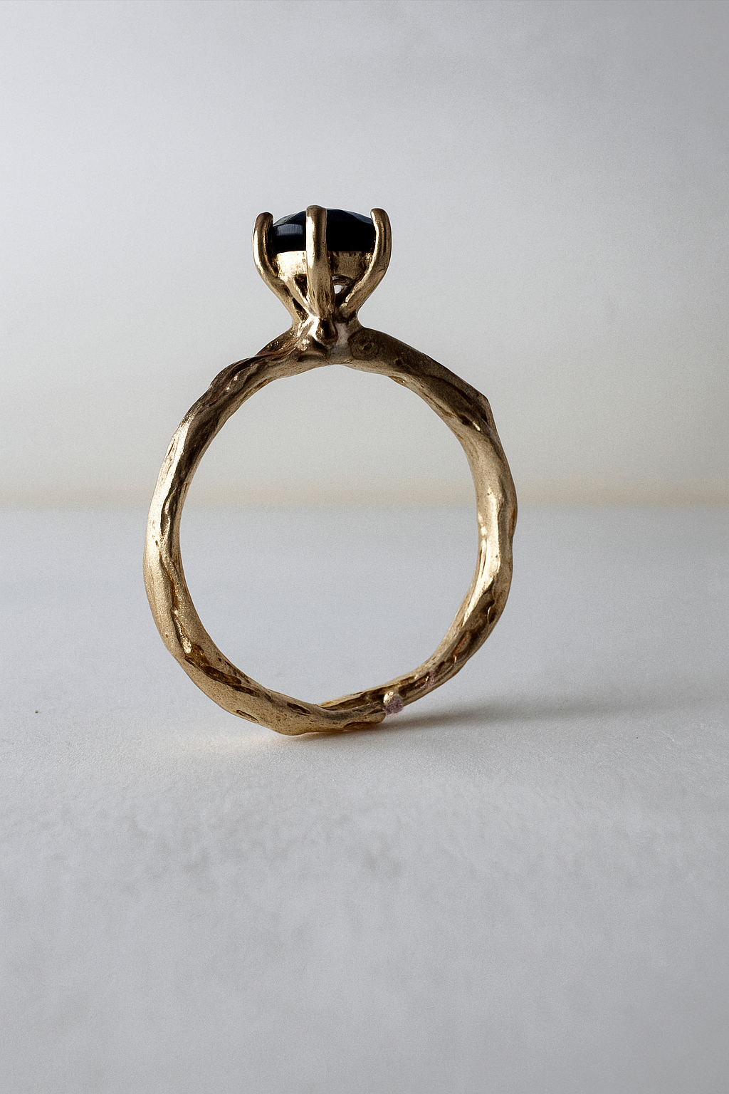Anillo de oro amarillo 10k con topacio Londres engastado en una banda orgánica esculpida, visto de frente sobre fondo claro.