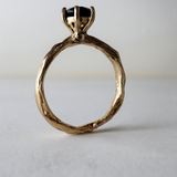 Anillo de oro amarillo 10k con topacio Londres engastado en una banda orgánica esculpida, visto de frente sobre fondo claro.
