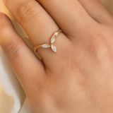 Anillo Marqueza en oro rosado con circones puesto en una mano, fotografiado sobre tela suave.