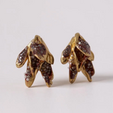 Par de aretes topos Nebula Mini en bronce bañado en oro, pintados a mano en  rust y con granulación de vidrio, sobre fondo blanco.