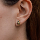 Primer plano lateral de la oreja de una mujer con arete topos Nebula Mini en bronce bañado en oro, pintado a mano en verde  con granulación de vidrio, cabello recogido contra un fondo neutro.