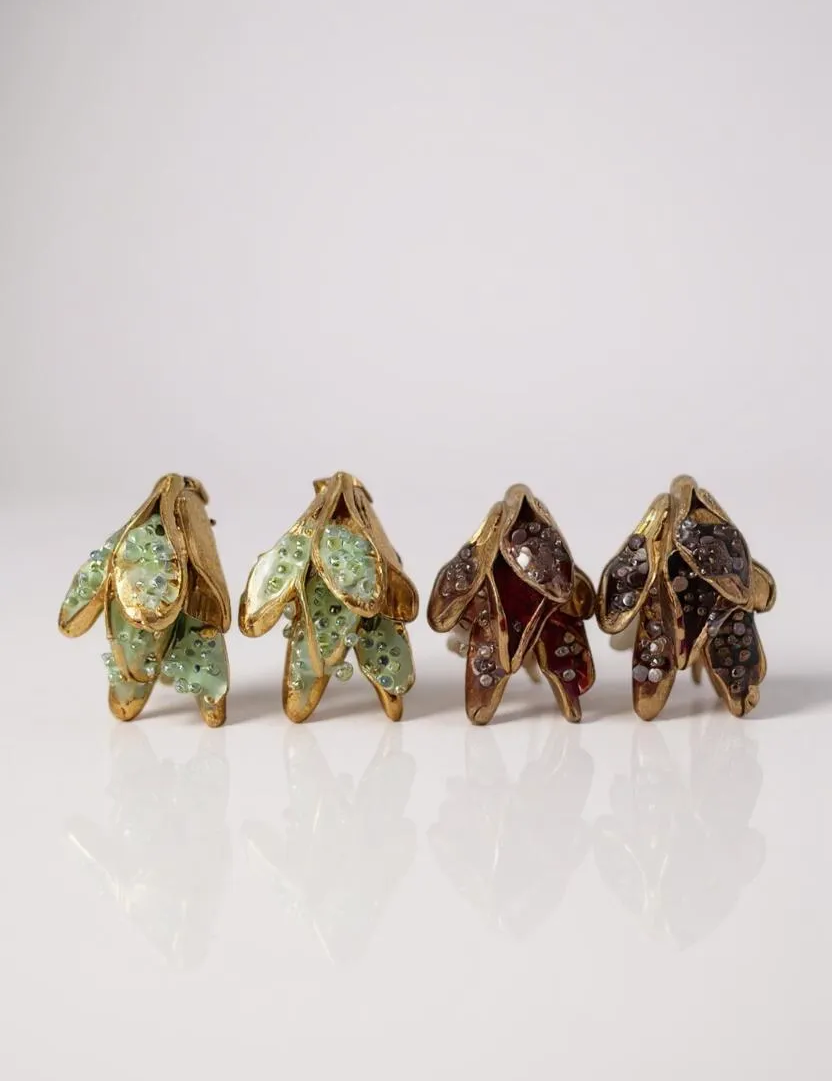 Disposición plana de cuatro aretes Topos Nebula Mini en forma de hoja alineados sobre fondo blanco: dos pintados a mano en verde y dos en rust, cada uno con granulación de vidrio y montura de bronce bañado en oro.