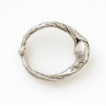 Anillo de plata esterlina con piedra del sol puesto en una mano, fotografiado sobre fondo gris claro